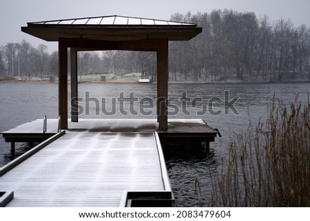 Wooden gazebo in the pier on the river with cape and iced fog over water in the background. Royalty-Free Stock Photo #2083479604