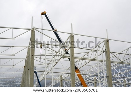 crane with telescopic boom in the assembly of metal structures of an industrial building Royalty-Free Stock Photo #2083506781