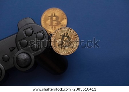 Crypto gaming concept. Video game controller with a bitcoin cryptocurrency coin Royalty-Free Stock Photo #2083510411