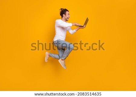Full length photo of impressed brunet young guy run write laptop wear shirt jeans footwear isolated on yellow background