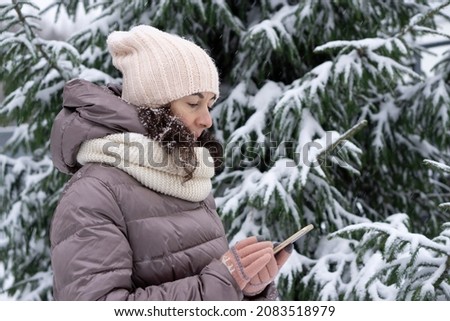 Outdoor winter portrait. Beautiful woman 45 years old talking on a cell phone in a snowy winter park