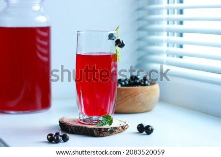 black currant juice with a glass glass on the window in the shade of the blinds, berries, summer soft drinks, healthy food. Royalty-Free Stock Photo #2083520059