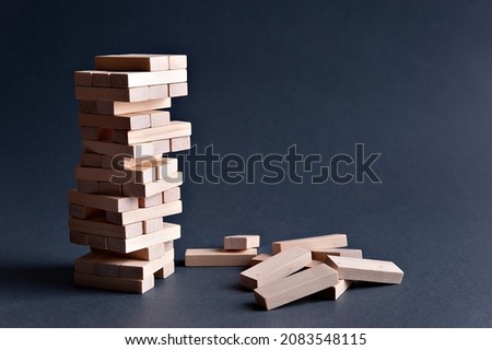 Jenga tower made of wooden blocks on gray-blue background, space for text Royalty-Free Stock Photo #2083548115