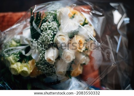 Wedding bouquet protected from rain in transparent shield paper with raindrops on top