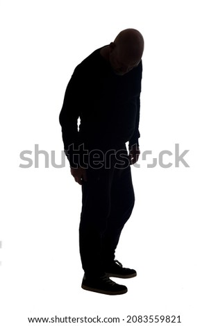 side view of the silhouette of a man wearing casual looking the floor