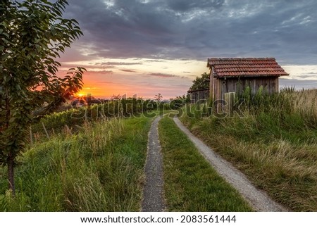 old wooden hut in countryside at sunset Royalty-Free Stock Photo #2083561444