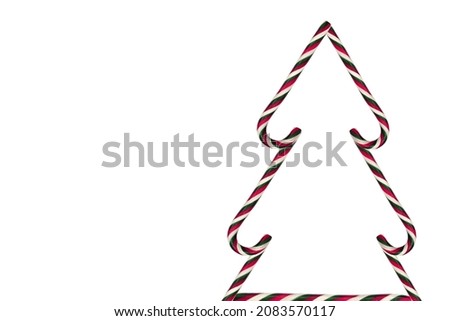 Christmas tree made of sweet caramel sticks. Christmas and New Year concept. Christmas tree made of caramels isolated on a white background.
