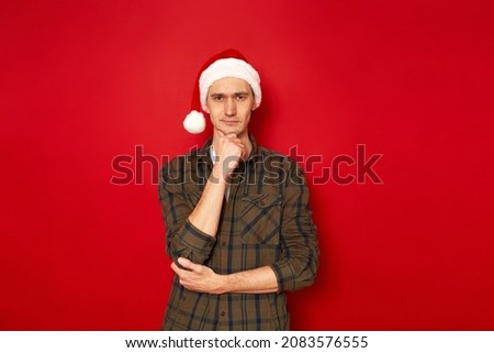 man holds chin his hand in casual clothes green shirt in thoughtful pose makes difficult choice isolated red background space for advertising text concept - brainstorming, idea, comparison, analysis