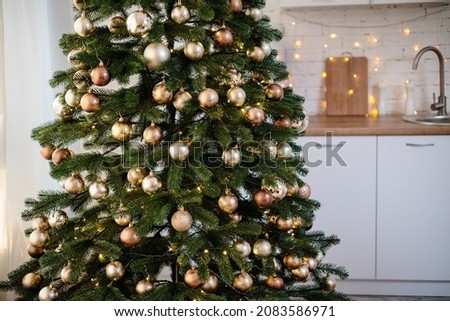 The tree is decorated with colorful toys and a garland. Close-up photo in warm colors. Christmas and New Year atmosphere