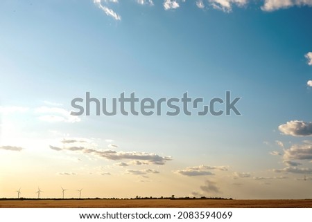 Sky with white clouds in warm colors with part of a wheat yellow field at sunset