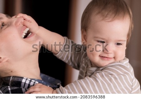 Portrait Adorable Face Of Little Cheerful Happy Toddler Daughter baby Charming Smile Look At Mom Strong Cuddles Loving Mommy Together. child catches holding mom by nose sincere feelings love care