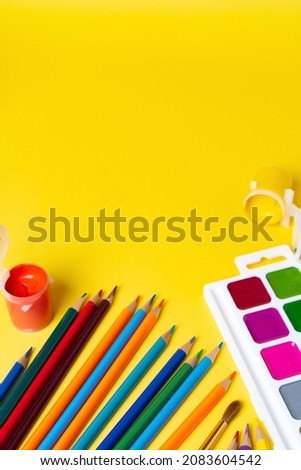 bright colored pencils and paints for drawing on a yellow background, the concept of creativity and inspiration
