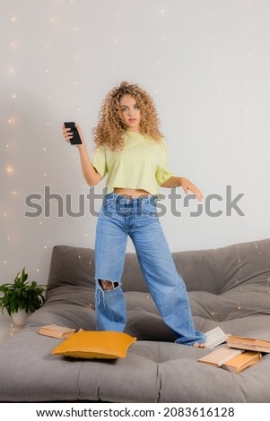 girl student has taken break from preparing for exams and is dancing and having fun among the books scattered on the gray sofa. concept of education and recreation. space for text. High quality photo