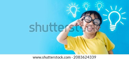 Smart kid nerd asian boy child with light bulb have good idea.Happy student kid thinking creative on blue banner background.Brainstorming and idea concept.online learning imagination innovation.stem. Royalty-Free Stock Photo #2083624339