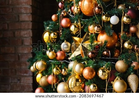 Selective focus. Decorations golden balls, beads and a big star on the Christmas tree near the brick wall.