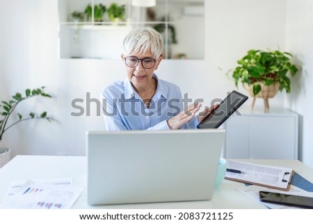Focused businesswoman presenting charts and graphs on video call online. business, technology and people concept, Mature businesswoman with papers having video conference by laptop computer at office