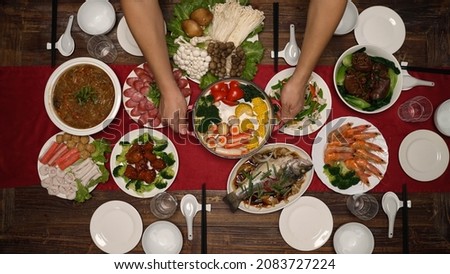 high angle view with fast forward hands serving freshly cooked chinese cuisines on the dining table in preparation for new year's eve dinner Royalty-Free Stock Photo #2083727224