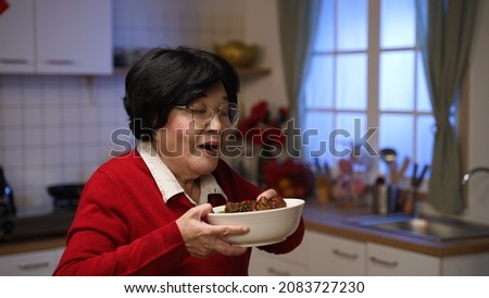 elderly mother serving freshly cooked food for reunion dinner and enjoying its good smell. walking out one by one on background of a modern kitchen