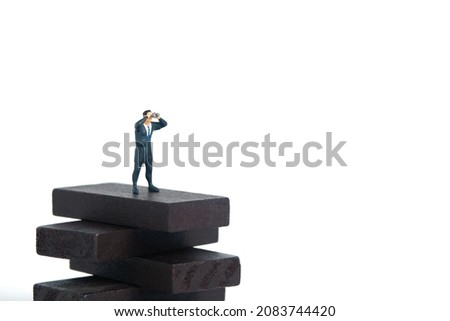 Businessman using binoculars standing above wooden obstacle stairway. Miniature tiny people toys photography. isolated on white background.
