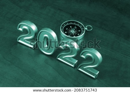 Compass and numbers 2022 on wooden table.