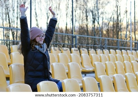 A fan girl happily throws her hands up on the podium