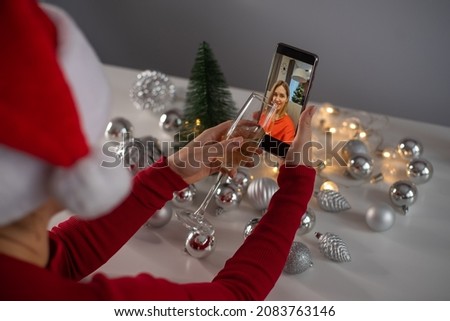 Women drink champagne celebrate Christmas and communicate remotely by smartphone