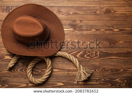 Cowboy hat and rope on wooden background