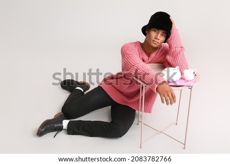 Stylish young African-American man on light background