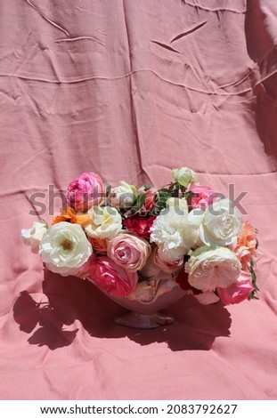 Bunch of beautiful old world roses in vase on pink linen background