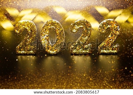 Holiday background 2022 New Year. Golden 2022 number sparkling glitter Christmas on black textured background with blurred bokex. Festive concept. Texture Gold glitter.