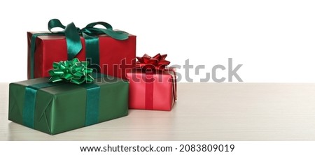 Red and green gift boxes on wooden table against white background, space for text