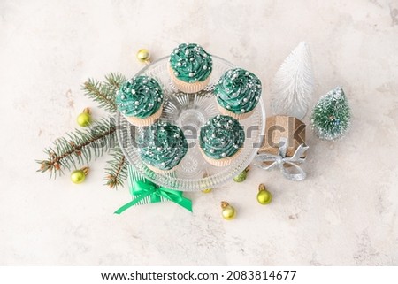 Tasty Christmas cupcakes and decor on table