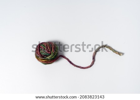 Glowing multicolored ball of yarn with loose thread on white background