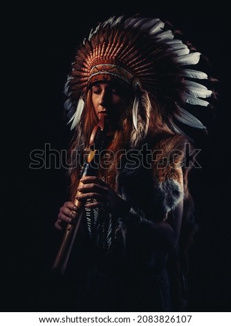 beautiful shamanic girl playing on shaman flute in the studio. Royalty-Free Stock Photo #2083826107