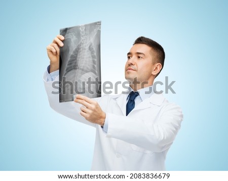 medicine, pet and healthcare concept - middle aged male veterinarian doctor looking at animal's x-ray over blue background Royalty-Free Stock Photo #2083836679