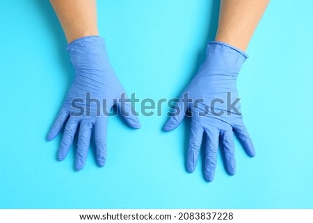 Hands in protective gloves on color background
