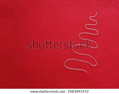 Christmas tree made of wire - silhouette, on a red background of felt. Christmas and New Year