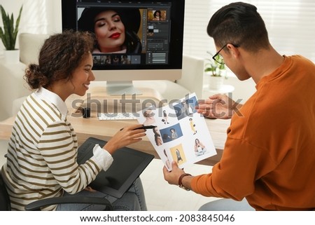 Professional retoucher with colleague working at desk in office
