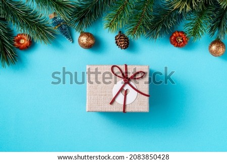 Top view of Christmas background design concept with gift box and fir tree branch decoration on blue table background.