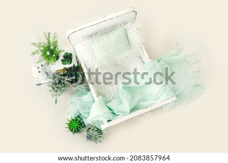 Newborn baby studio furniture bed for infant child photoshoot with fur and pillow decorated with plants and lavander. Tiny designed scene for kid studio portrait, view from above