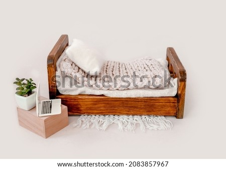 Wooden bed decor for newborn studio photoshoot with knitted blanket and pillow closeup. Infant baby photo furniture and toy laptop