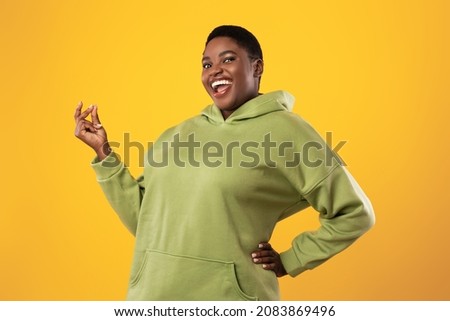 Joyful Overweight Black Woman Snapping Fingers Smiling To Camera Standing Posing Over Yellow Studio Background. It's Easy, Finger Clicking Gesture Concept Royalty-Free Stock Photo #2083869496