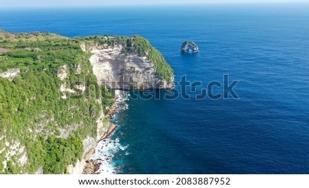 Drone footage of the west coast of Nusa Penida, Indonesia with hindu temple built on top of vertical cliffs, a small path is going to it on the edge.