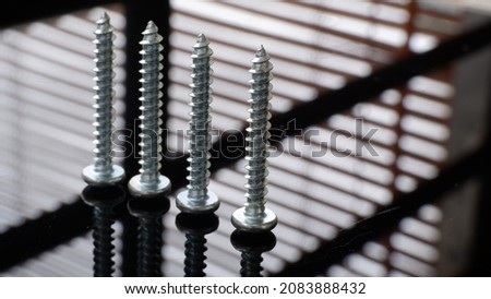 Four neatly arranged bolts with a soft window shade. Macro photography. Selected focus. 