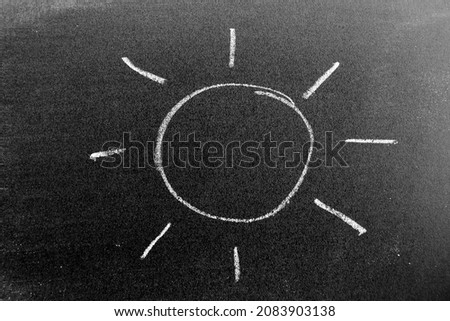 White color chalk hand drawing in sun with ray shape on black board background