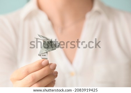 Woman with origami bird made of dollar banknote, closeup