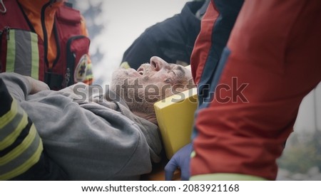 Paramedics carrying injured man after disaster Royalty-Free Stock Photo #2083921168
