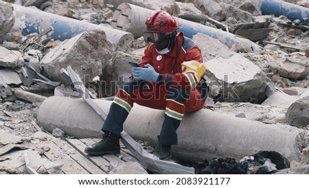 Black paramedic using smartphone after disaster Royalty-Free Stock Photo #2083921177