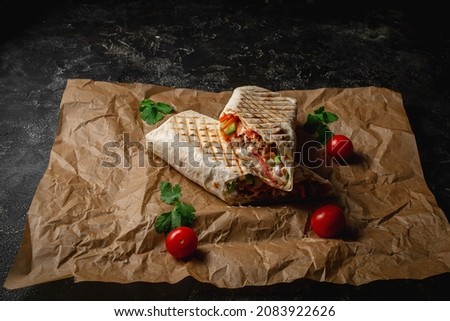 Delicious shawarma and lavash tacos on a dark stone table. Fast food restaurant. Healthy option of fast food. Tasty fresh wrap sandwiches with beef meat and vegetables, Traditional snack