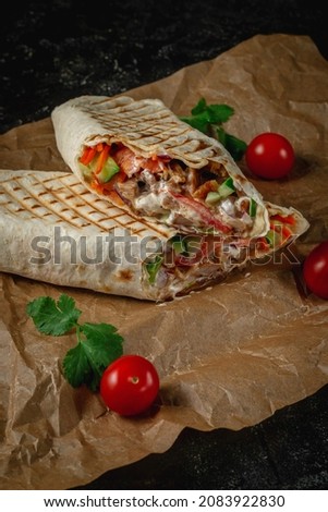 Delicious shawarma and lavash tacos on a dark stone table. Fast food restaurant. Healthy option of fast food. Tasty fresh wrap sandwiches with beef meat and vegetables, Traditional snack
